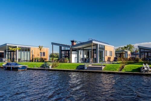 ein Haus am Wasser neben einem Fluss in der Unterkunft Recreatiepark Tusken de Marren in Akkrum