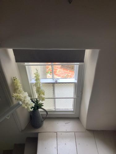 a vase of flowers sitting in front of a window at 1A River Cottage, Baslow in Baslow