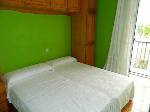 a green bedroom with a bed with a green wall at Antia - Casita de piedra en Lariño in Carnota