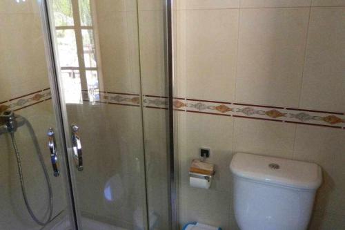 a bathroom with a shower and a toilet and a glass shower door at Casa Crina Casa restaurada con finca grande in Outes