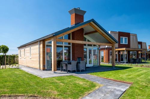a house with a conservatory on a lawn at Recreatiepark Tusken de Marren in Akkrum