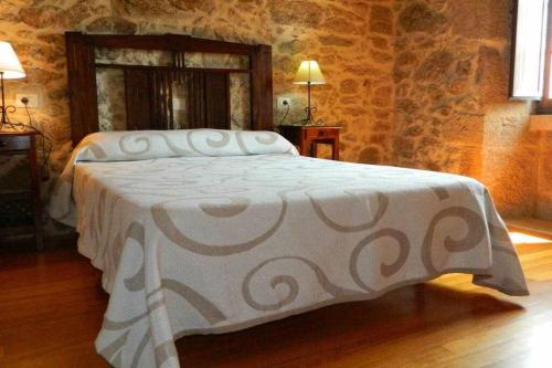 ein Schlafzimmer mit einem Bett in einer Steinmauer in der Unterkunft Casa Crina Casa restaurada con finca grande in Outes