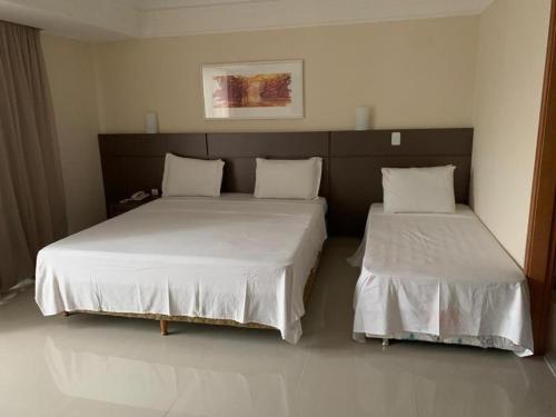 a bedroom with two beds with white sheets at Tropical Executive Hotel Flats in Manaus
