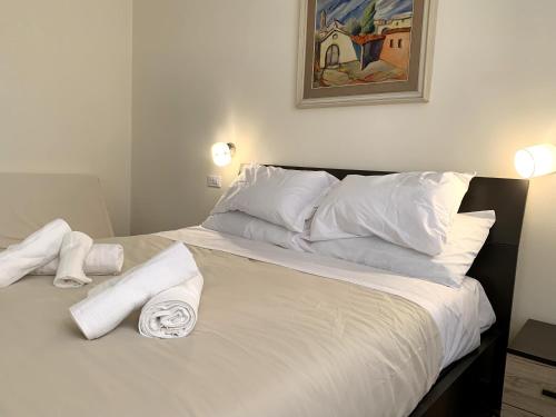 ein Bett mit weißen Kissen und Handtüchern darauf in der Unterkunft Domo Achenza in Terralba