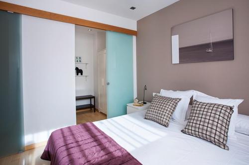 um quarto com uma cama branca e 2 almofadas em Durlet Rambla Mar Apartments em Barcelona