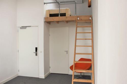 a small room with a chair and a ladder at Hostel Roots in Tilburg
