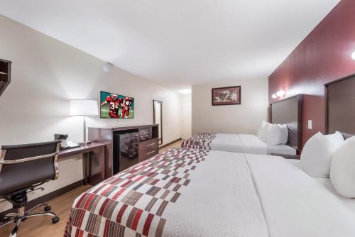 a hotel room with two beds and a desk at Red Roof Inn & Suites Denton in Denton