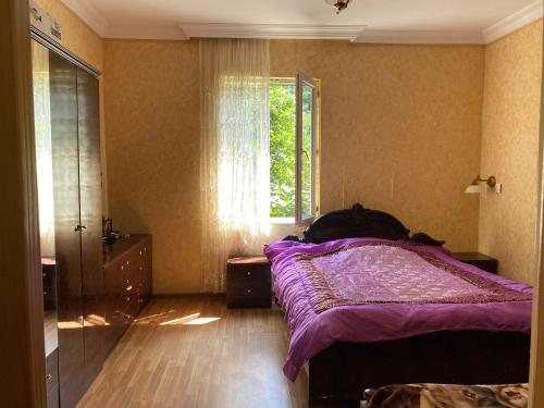 a bedroom with a purple bed and a window at Venera's Guest House in Batumi