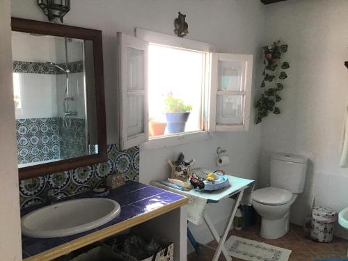 a bathroom with a sink and a toilet and a window at Casa Chantal in Gaucín