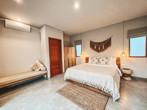 a bedroom with a bed and a bench in it at Kalia Bingin - Adult only in Uluwatu