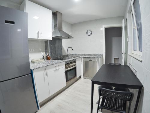eine Küche mit weißen Schränken und einer schwarzen Arbeitsplatte in der Unterkunft Bonito piso Villafria in Oviedo
