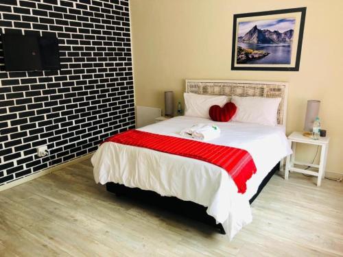 a bedroom with a large bed with red pillows at FM GUEST LODGE Comfort, Tranquility & Peace of Mind in Johannesburg