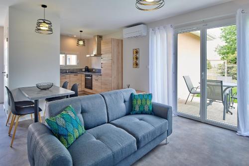 un salon avec un canapé bleu et une table dans l'établissement Casa Lhosa Villa patio 3 étoiles, à Saint-Paul-lès-Dax