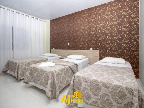 1 dormitorio con 2 camas y pared con papel pintado con motivos florales en AJ Hotel Chapecó - Fácil Acesso Pátio Shopping e Rótula da Bandeira, en Chapecó