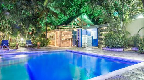 a blue swimming pool with two chairs and palm trees at Hotel Santorini Express y Cabañas in Santa Marta