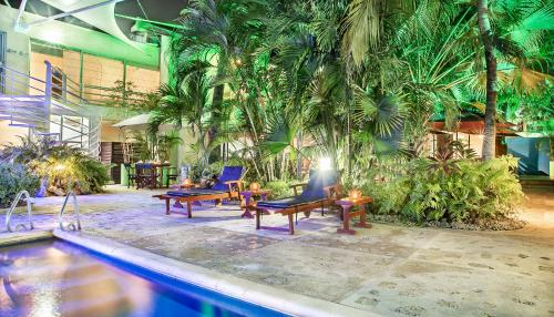 a swimming pool with chairs and tables and palm trees at Hotel Santorini Express y Cabañas in Santa Marta