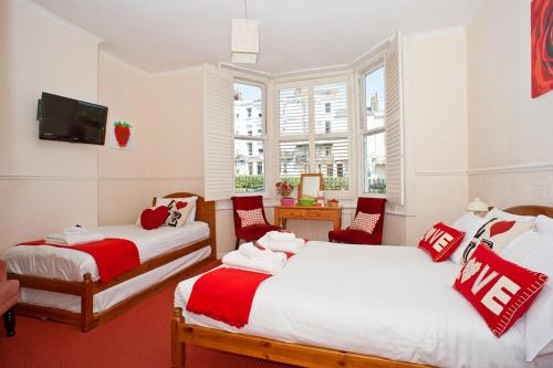 a bedroom with two beds with red and white pillows at Strawberry Fields in Brighton & Hove