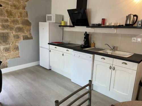 サルラ・ラ・カネダにあるAppartement* authentique meublé Sarlat coeur villeの白いキャビネット、シンク、カウンター付きのキッチン