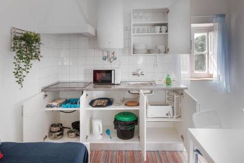 una pequeña cocina con armarios blancos y fregadero en T Monte en Porto Covo