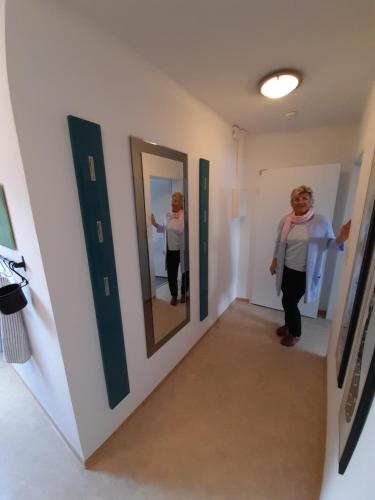a woman is standing in a hallway in front of mirrors at Thoreys Ferienwohnung in Soltau in Soltau