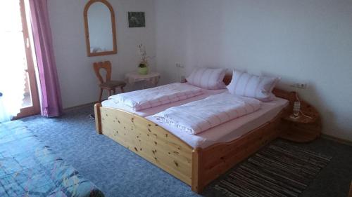 sypialnia z drewnianym łóżkiem z białymi poduszkami w obiekcie Ferienwohnung Piller w mieście Hohenau
