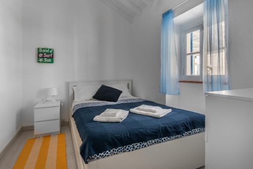 - une chambre avec un lit doté de draps bleus et une fenêtre dans l'établissement T Monte, à Porto Covo