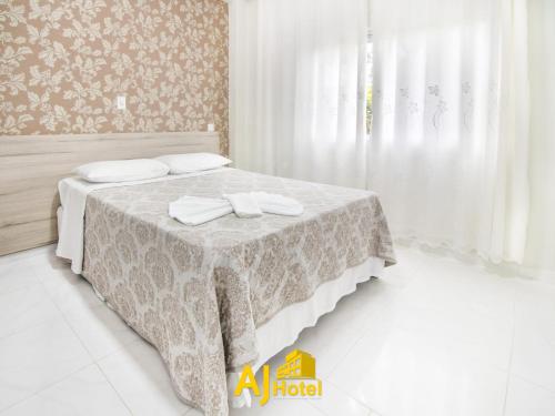 um quarto com uma cama com uma mesa branca e toalhas em AJ Hotel Chapecó - Fácil Acesso Pátio Shopping e Rótula da Bandeira em Chapecó