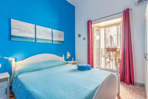 um quarto azul com uma cama e uma janela em Il riad del capitano em Siracusa