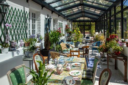 un patio avec une table, des chaises et des plantes dans l'établissement villa marguerite 65 rue legout lesage 76260 ponts et marais, à Ponts-et-Marais