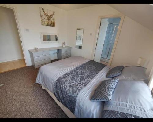 ein Schlafzimmer mit einem Bett, einer Kommode und einem Fenster in der Unterkunft Portrush Penthouse Stunning Harbour & Atlantic Views only 2 mins walk to Harbour & Ramore in Portrush