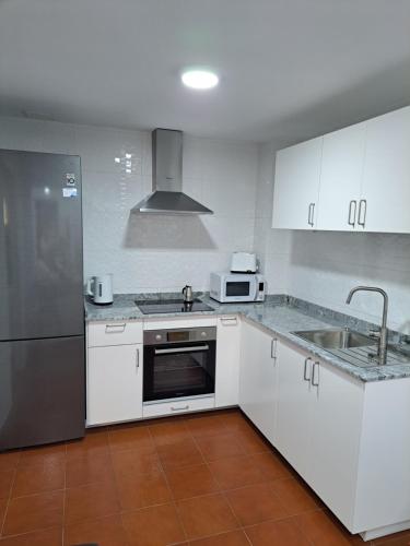 una cucina con armadi bianchi e frigorifero in acciaio inossidabile di Casa Abian ad Arrecife
