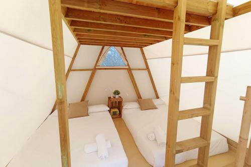 um quarto no sótão com uma cama e uma escada em Kampaoh Cabañeros em Navas de Estena