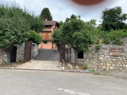 una casa con una pared de piedra y un camino de entrada en appartement avec Jacuzzi hammam sauna privatisé au rez de chaussée ds maison à Voglans à 2 kilomètres du lac du bourget en Savoie entre Chambéry et Aix les Bains cure thermale en Voglans