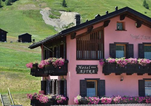 a pink house with flower boxes on the windows at Hotel Astra in Livigno