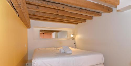 Una cama blanca en una habitación con techos de madera. en Appart'Parchemin, en Lyon