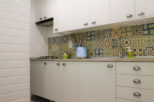 a kitchen with white cabinets and tiles on the wall at NatureHouse in Campo Maior