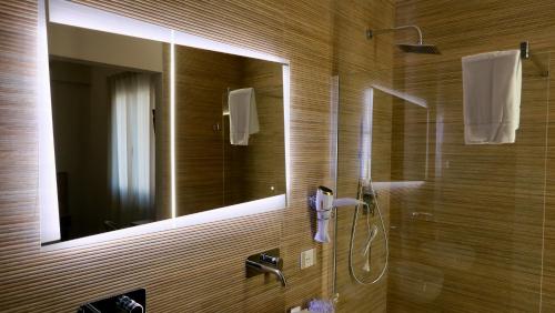 uma casa de banho com um chuveiro e um espelho. em Oneira Rooms em Agrigento
