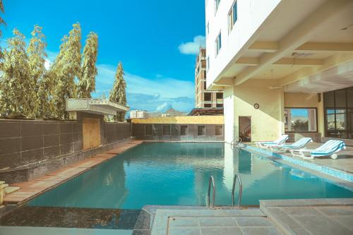 a swimming pool with chairs and a building at Hotel Yois in Udaipur