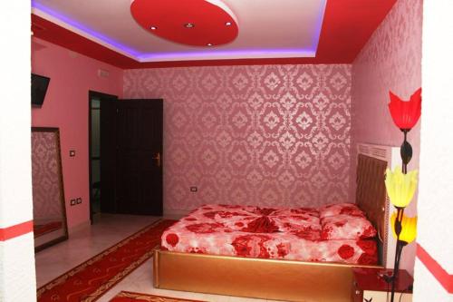 a bedroom with a red bed and a pink wall at Hotel Buza in Shkodër