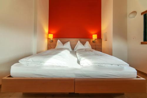a bedroom with a bed with a red wall at Hotel Ucliva in Waltensburg