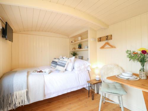 sypialnia z białym łóżkiem i stołem w obiekcie High Grounds Shepherd's Hut w mieście Ashbourne