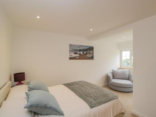 een witte slaapkamer met een bed en een stoel bij Dorset View in Blandford Forum