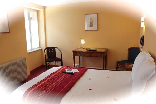 a bedroom with a bed with a desk and two chairs at Hôtel Restaurant La Cigogne in Munster