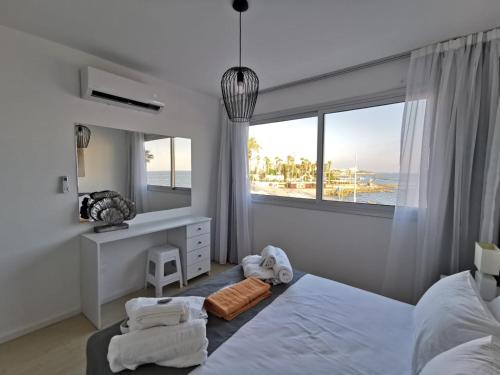 a white bedroom with a bed and a window at COSea Living: Seaside Two Bedroom Flat in Harbour 106 in Paphos City