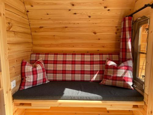Bett in einer Hütte mit zwei roten Kissen in der Unterkunft Timmi Lake in Timmendorfer Strand