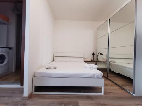 een witte slaapkamer met een bed en een spiegel bij Monolocale - Piano terra - Ingresso indipendente in Padua