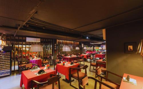 un ristorante con tavoli e sedie rossi in una stanza di Hotel Emerald Waters Classy a Hanoi