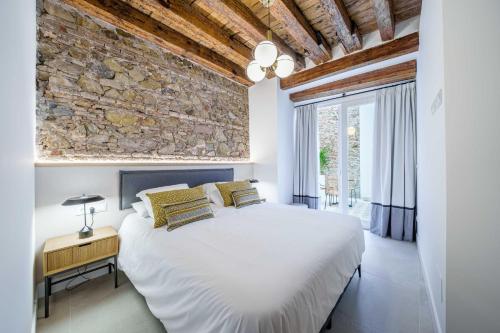 um quarto com uma cama branca e uma parede de pedra em Homely Málaga Mariblanca 17, Vegafuente Apartments em Málaga