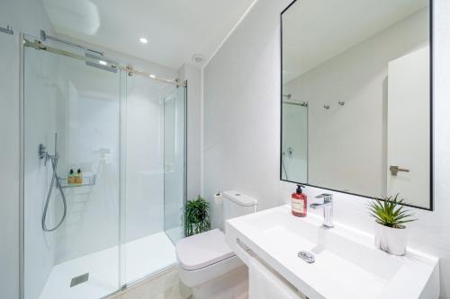 a white bathroom with a sink and a shower at Homely Málaga Mariblanca 17, Vegafuente Apartments in Málaga