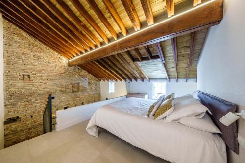 a bedroom with a large bed and a brick wall at Homely Málaga Mariblanca 17, Vegafuente Apartments in Málaga